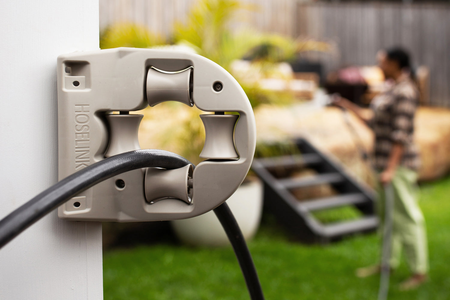 Warm Grey Hose Guide Attached To a Wall With Hose Fed Through It