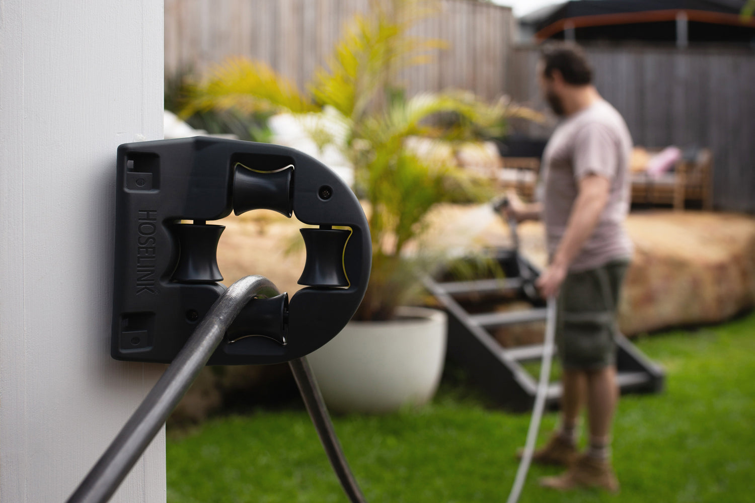 Charcoal Hose Guide With Man Using it To Stabilise His Hose and Water His Garden