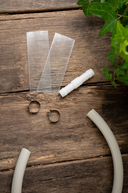 Flatlay of hose repair kit laid out on wooden bench with ivy creeping in