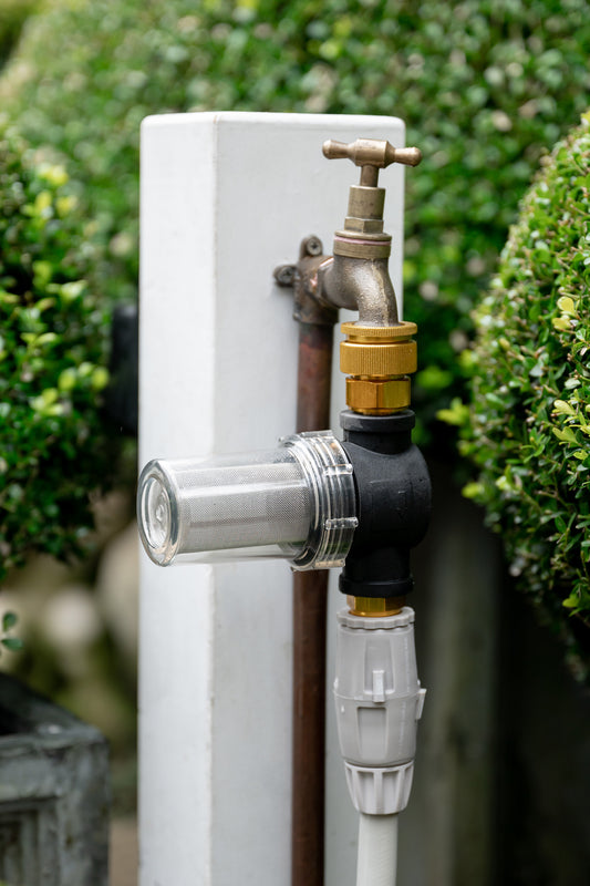 In-line water filter attached to tap and hose in garden