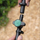 Close up of black and green irrigation valve being attached to irrigation pipe with 13mm ratchet clamps