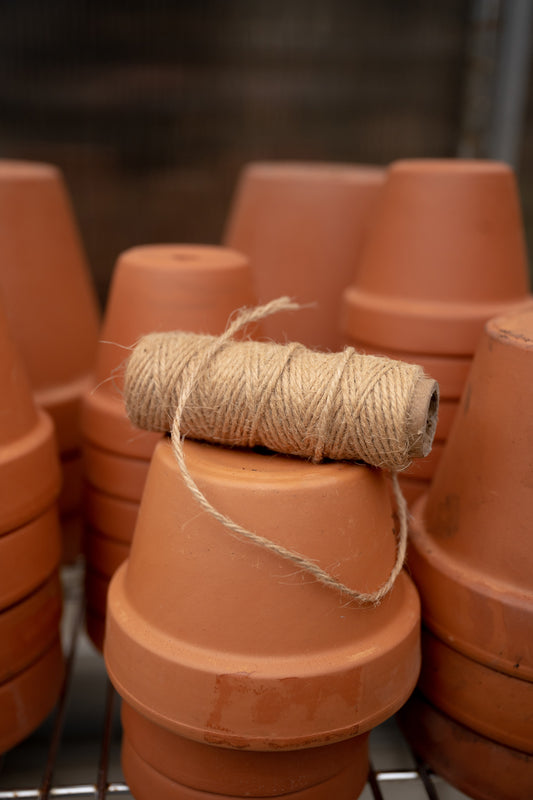 Jute garden twine resting on stacked terracotta pots in greenhouse