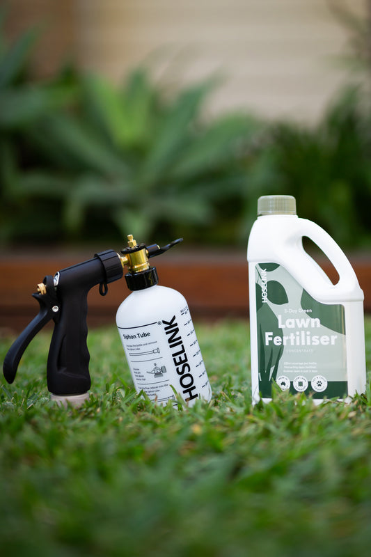 lawn fertiliser and fertiliser spray mixer on lawn next to eachother