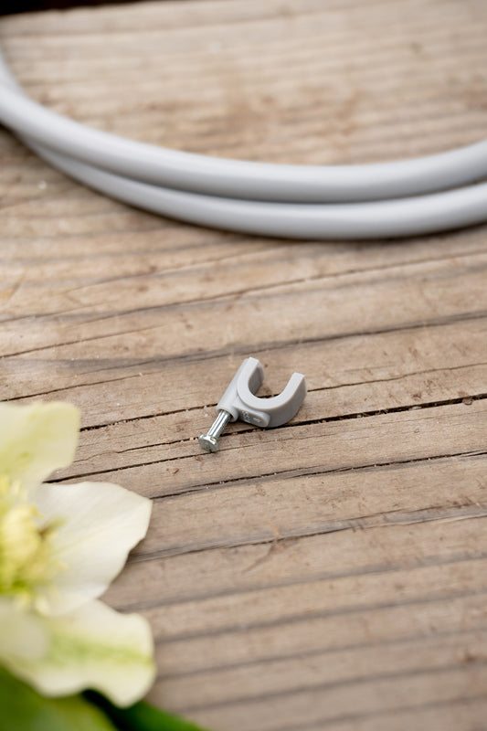 Close-up of misting installation pin on a bench with misting tube and hellebore flower in background