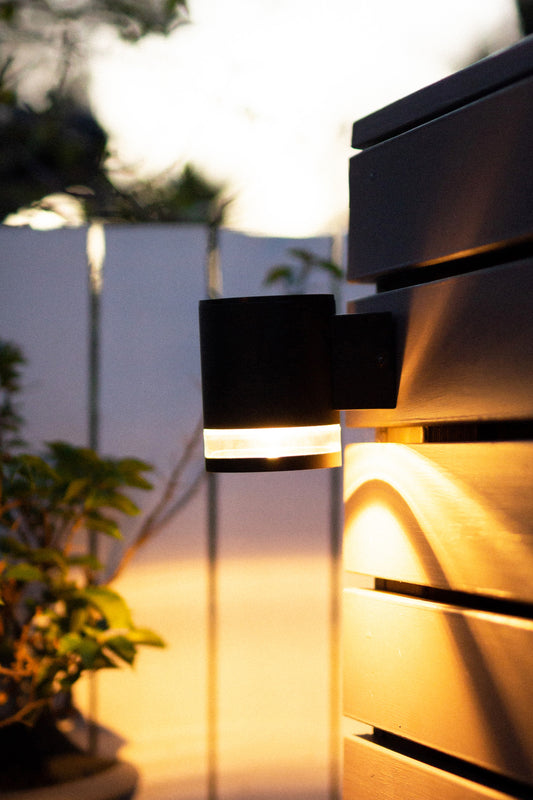 Modern solar wall light mounted on a wood-finish wall in garden