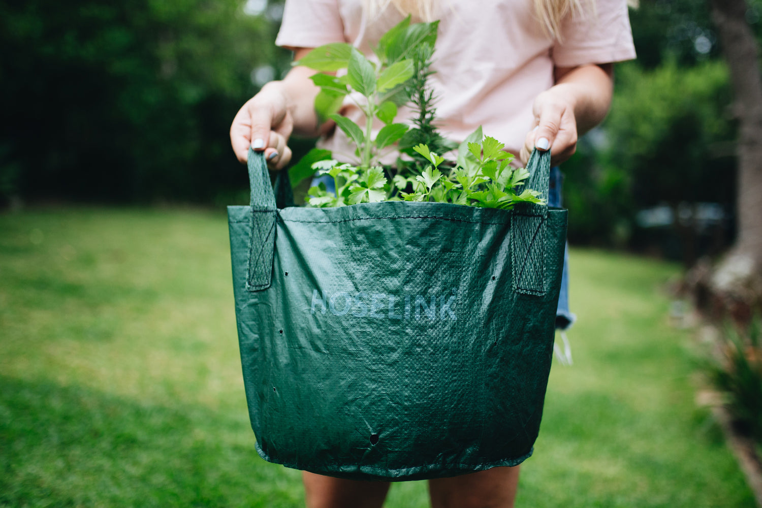 woman holding planter bag full of herbs on a lawn