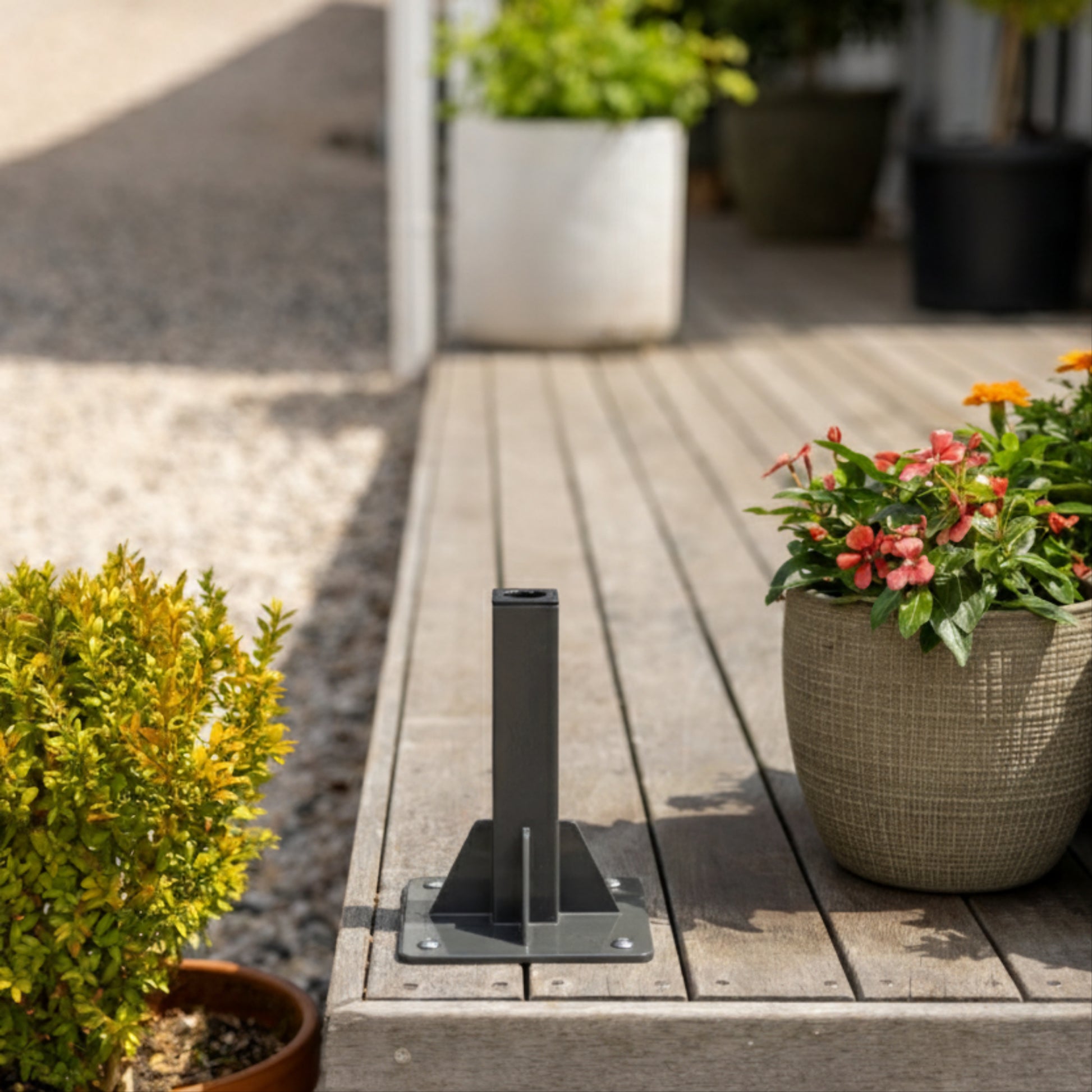 Charcoal classic hose reel grouns mount on the corner of a wooden deck with potted plants either side
