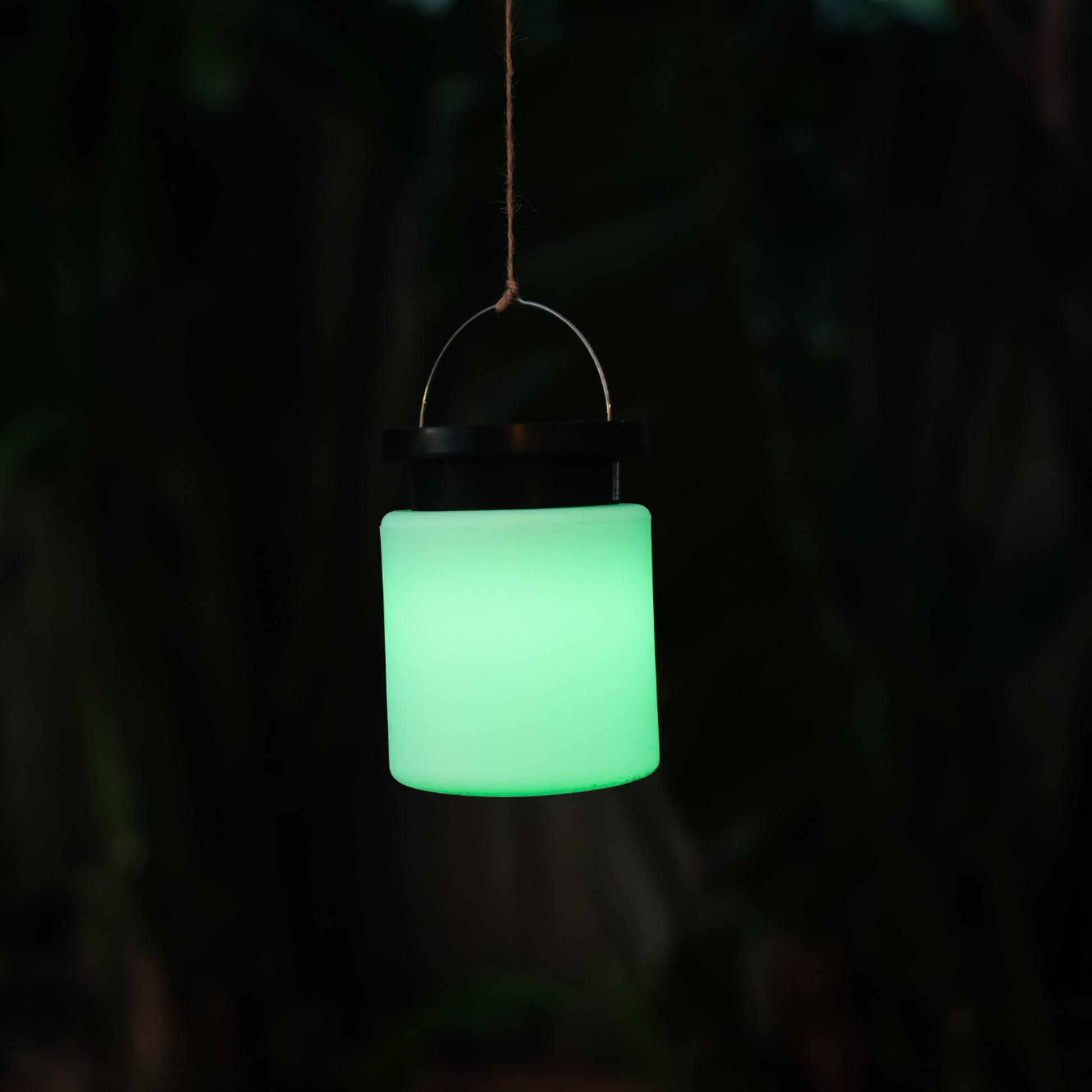 Solar camp light hanging from a string and shining green