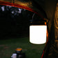 Solar Camp Light hanging in the doorway of a tent with grass outside