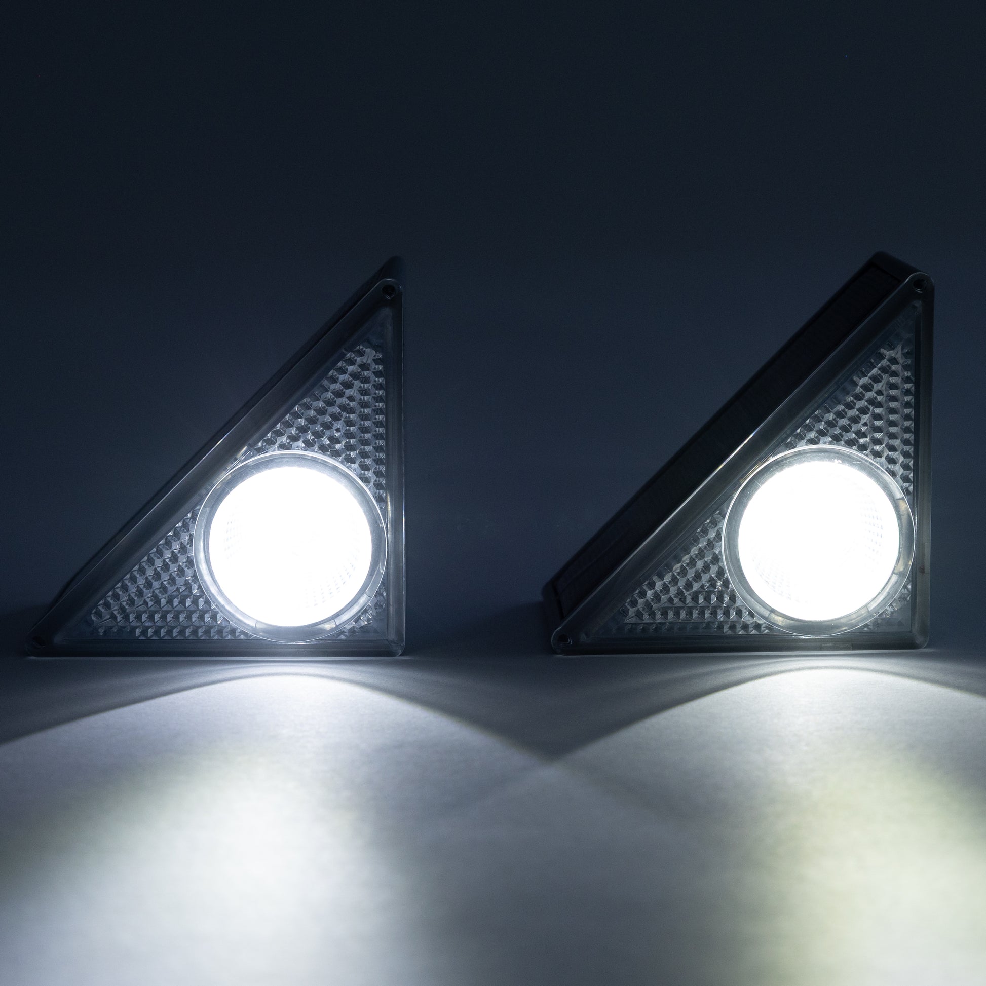 Two solar step LED lights on a dark background with light on
