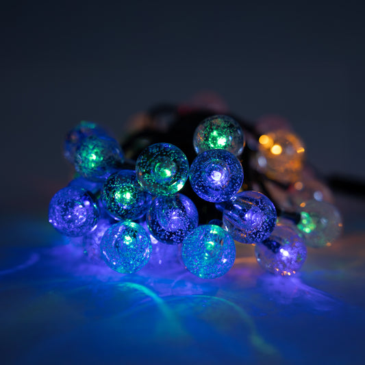 String of green and blue colored bauble lights on a dark background