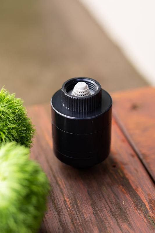 Black Hoselink water saver on a table with greenery surrounding 