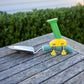 Green and yellow PETA Easi Grip Add-On Handle attached to a trowel on a deck