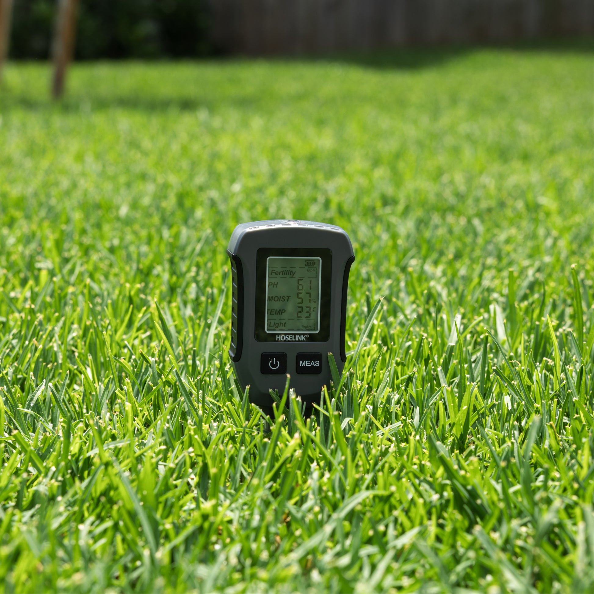 Soil meter turned on inserted into grass.