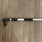 A close-up of a telescoping cleaning system pole with black textured grip sections and gutter cleaner head attachments laid horizontally on a brown wooden plank surface.