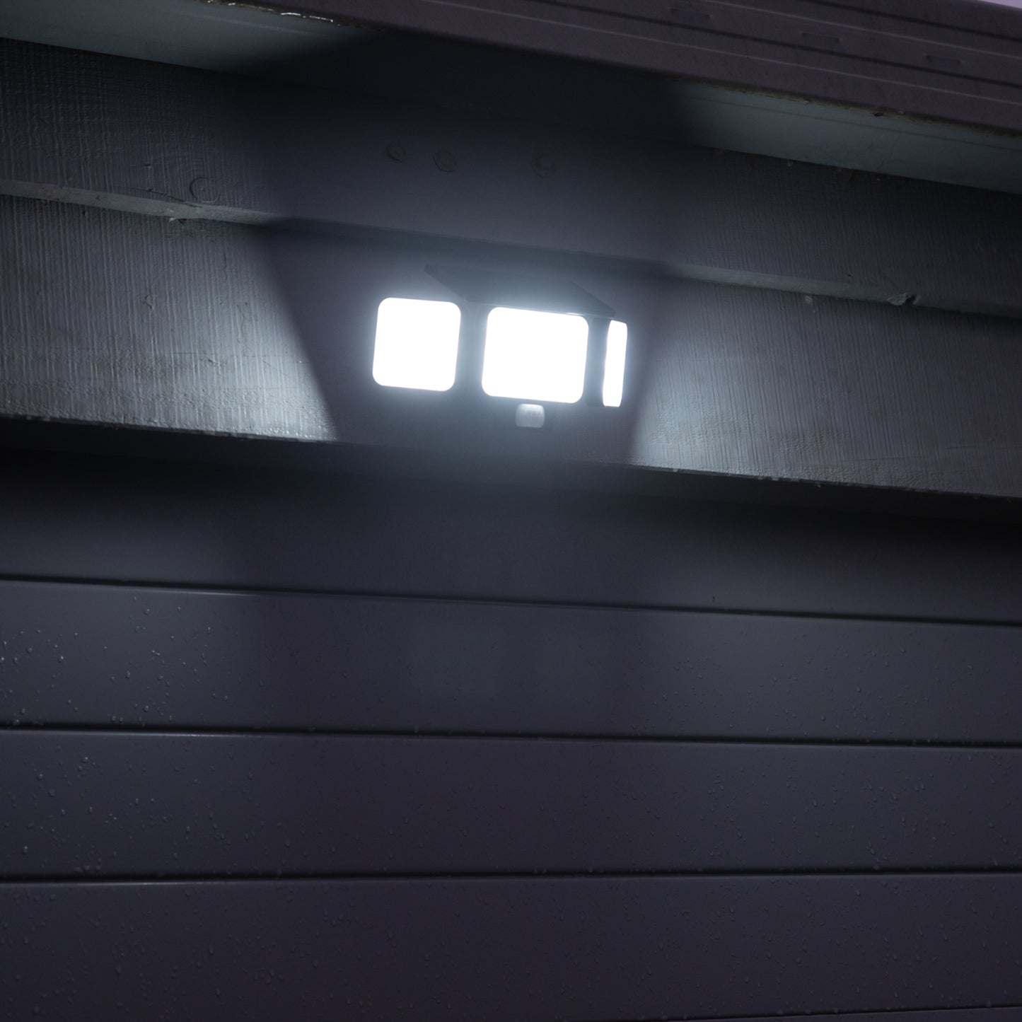 Solar Motion Floodlight above a blue garage door, illuminated. 
