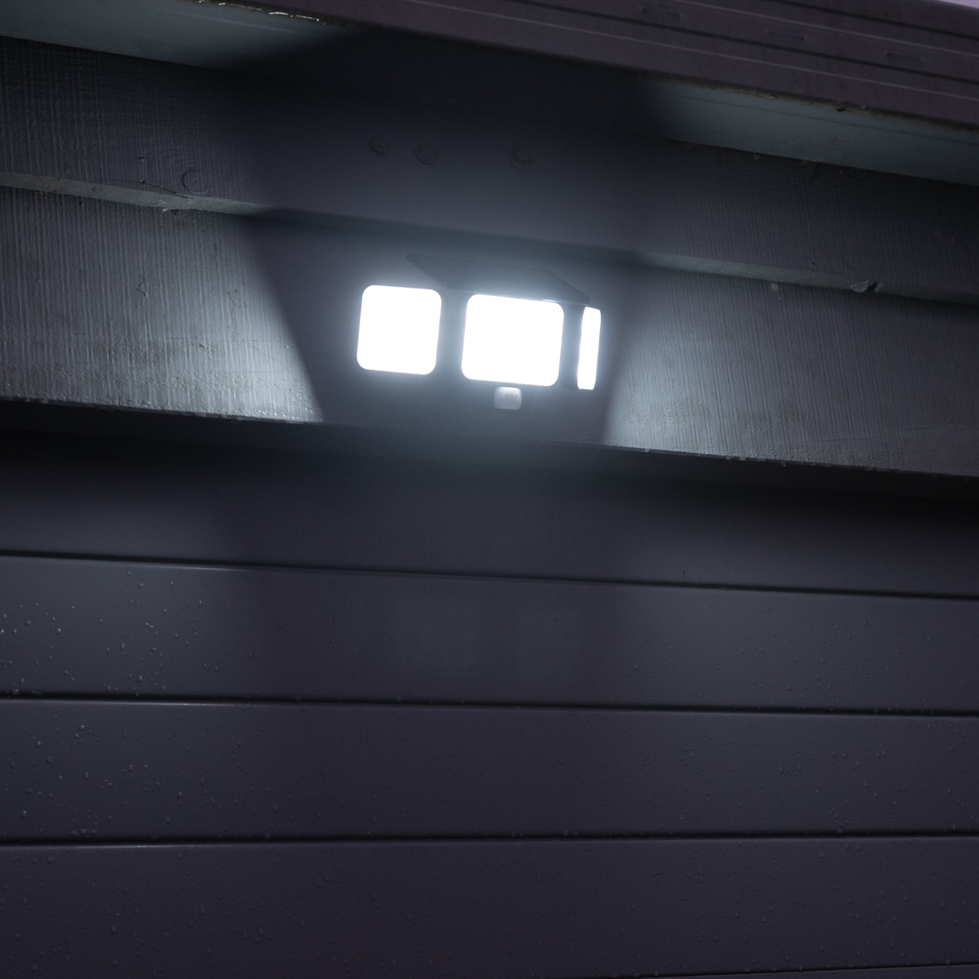 Solar Motion Floodlight above a blue garage door, illuminated. 