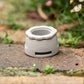 Close up of Gen 2 Universal Tap Connector with reducer. Resting on brown paving with blurred flowers in the background