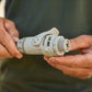 A close-up of a person's hands holding a light gray accessoryt connector with swivel with a threaded male end 