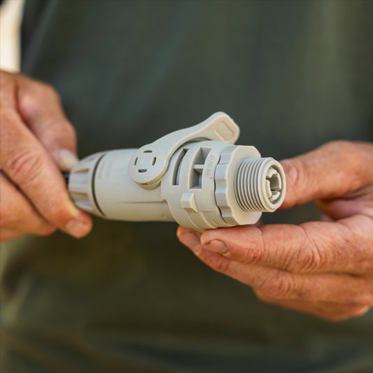 A close-up of a person's hands holding a light gray accessoryt connector with swivel with a threaded male end 