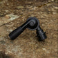 A matte black gutter cleaner head attachment with a threaded end, photographed resting on a textured stone surface.