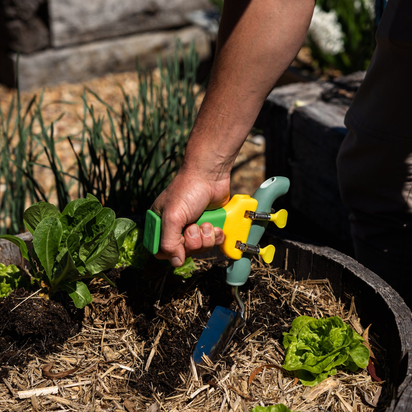 Green and yellow PETA Easi Grip Add-On Handle attached to a trowel digging in a pot
