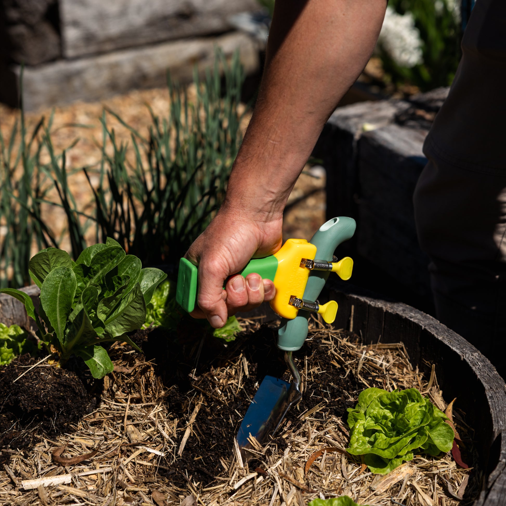 Green and yellow PETA Easi Grip Add-On Handle attached to a trowel digging in a pot