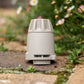 A HOSELINK Hose End Connector standing on a stone path with blurred flowers and greenery in the background.