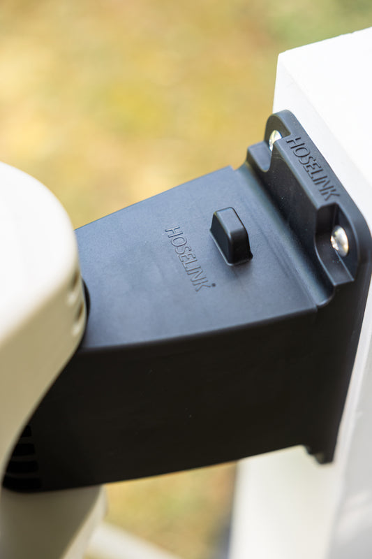 Close-up of black evolve bracket lid, installed in the bracket on a white white with a beige evolve retractable hosee reel attached