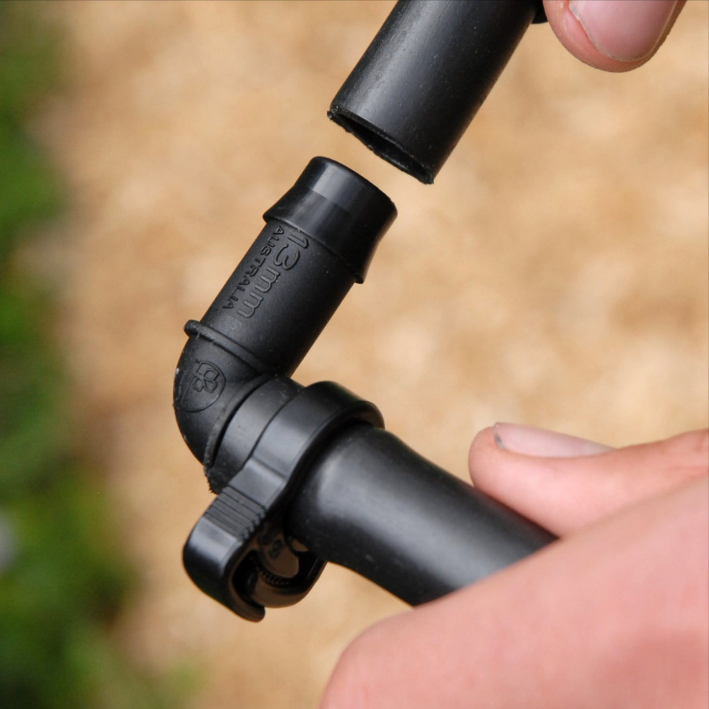 Cloes up of black irrigation elbow joint being installed into poly pipe with 13mm ratchet clamp on one end