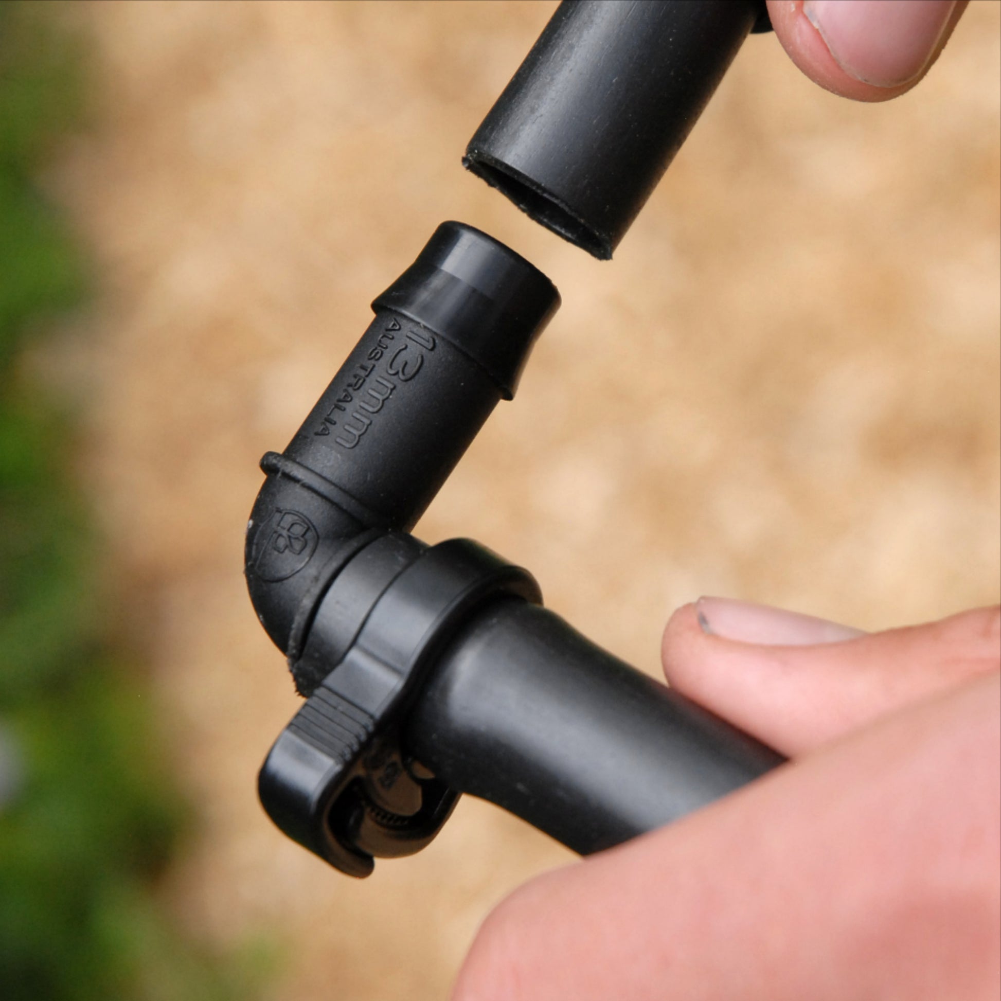 Cloes up of black irrigation elbow joint being installed into poly pipe with 13mm ratchet clamp on one end