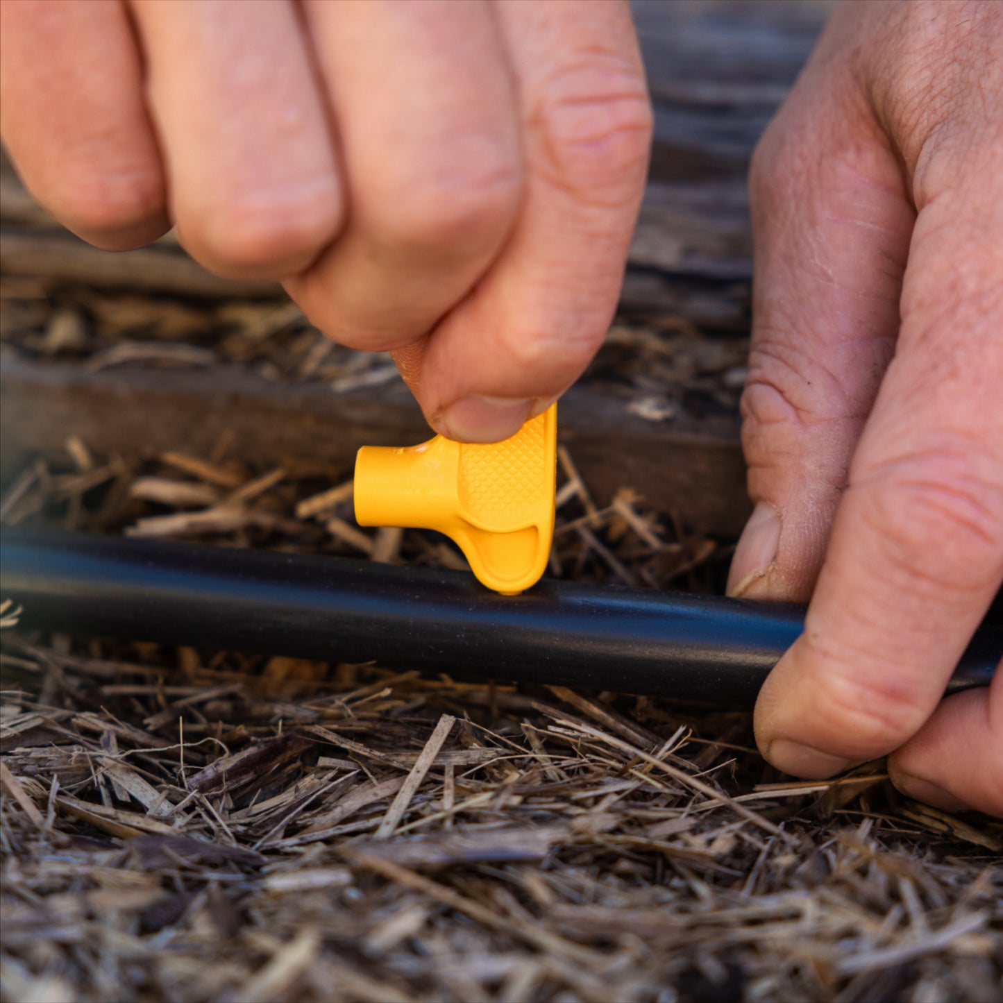 Yellow key punch inserted into hole in black pipe in a natural settinge