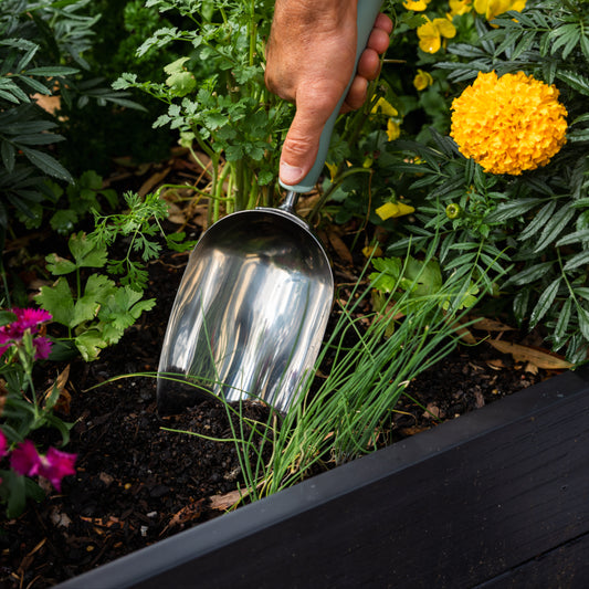 hand digging in the soil with a Large Potting Scoop.