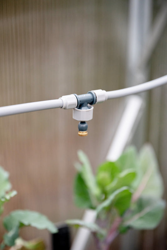 Misting system in-line directional head attached to misting tube sitting above edible plants