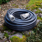 Coiled garden hose with connectors on a stone, mossy surface