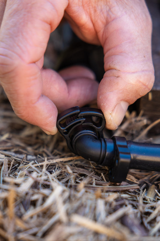 person tightening 13mm ratchet clamp on black irrigation tubing