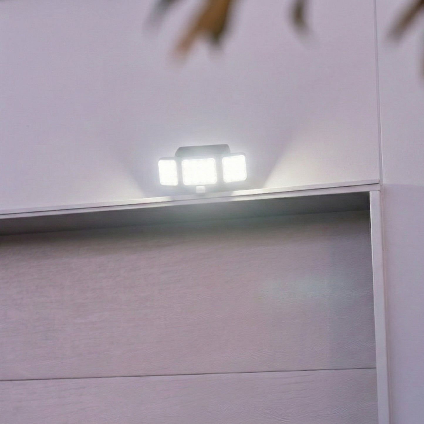 Solar Motion Floodlight above white garage door, illuminated.