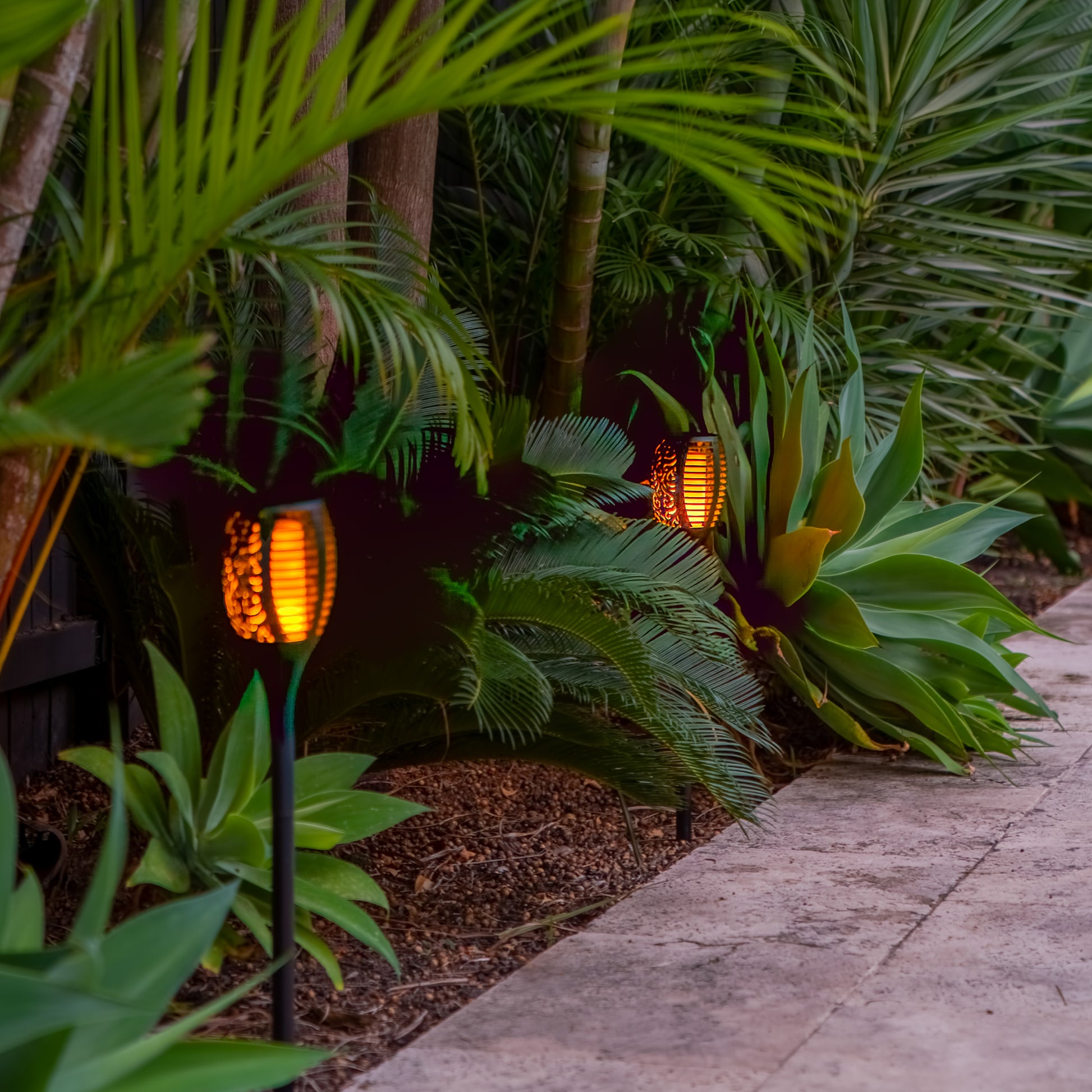 Two Solar Tiki Torch Lights installed in tropical garden