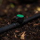 Close-up of a black irrigation pipe with a green valve on soil