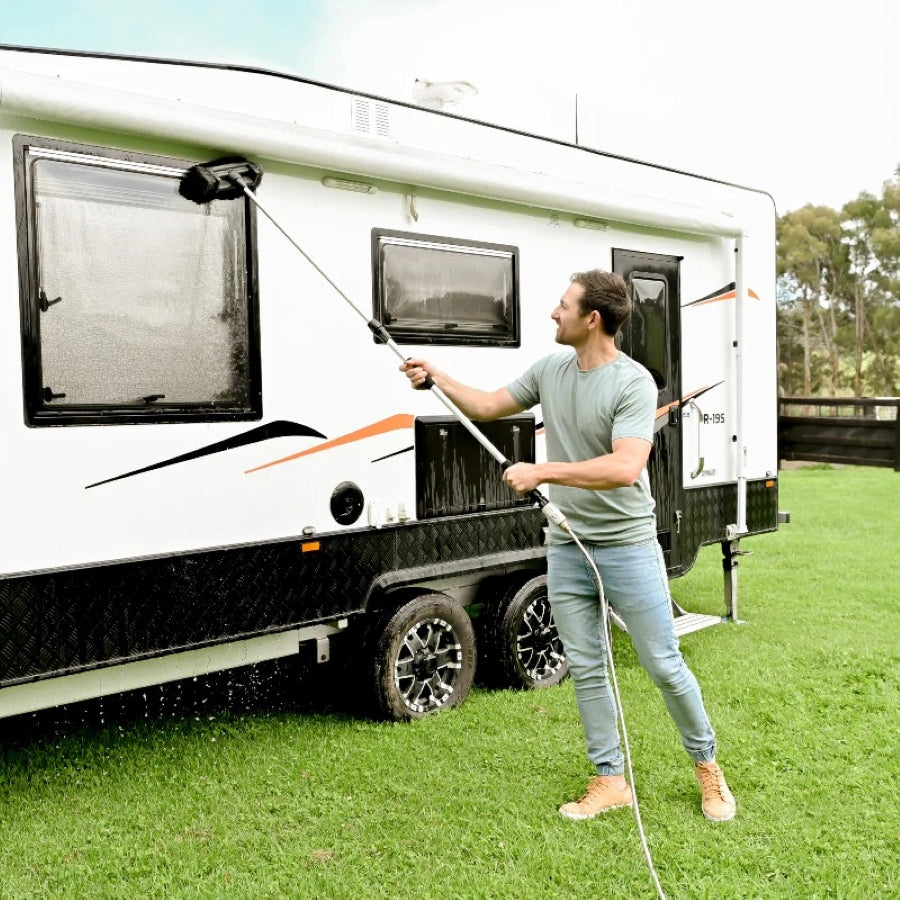 Extendable cleaning brush and soft head attachment being used to clean a white caravan in a backyard 