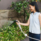 woman in blue top watering a garden bed with the compact flow nozzle